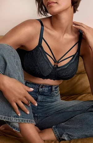 Soutien-gorge noir à dentelle avec jeu de liens, porté avec un jean décontracté.