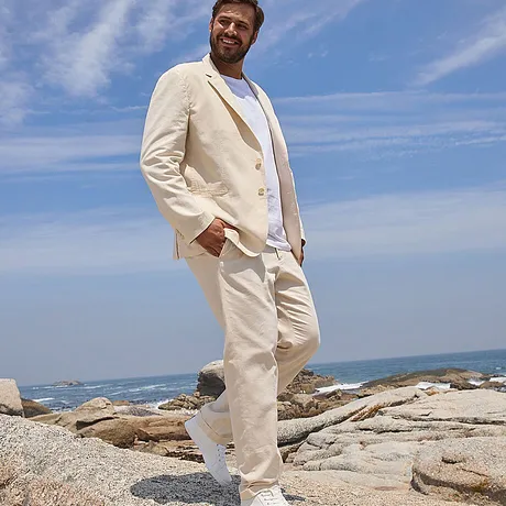 Costume estival élégant de couleur crème : blazer léger, pantalon et T-shirt blanc, chaussures claires assorties.