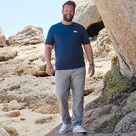 T-shirt bleu avec logo, pantalon gris et sneakers blanches.