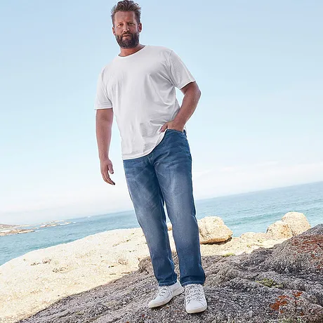 Look décontracté pour la plage : T-shirt blanc et jean confortable, complétés d'une paire de sneakers blanches.