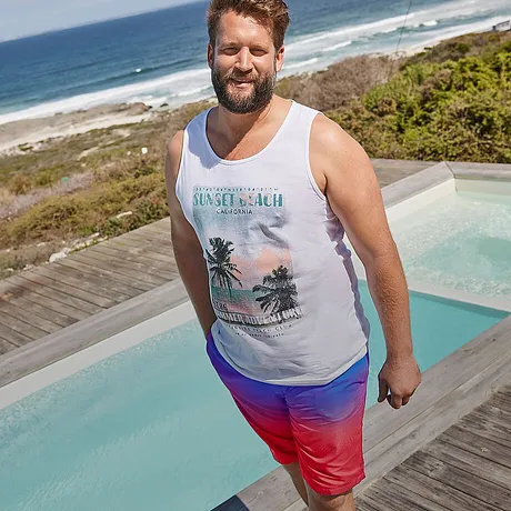 Débardeur blanc à imprimé tropical, short de bain coloré en rouge et bleu.