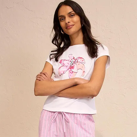 Weißes T-Shirt mit rosa Aufdruck, kombiniert mit gestreifter Pyjamahose. Lässiger und bequemer Look.