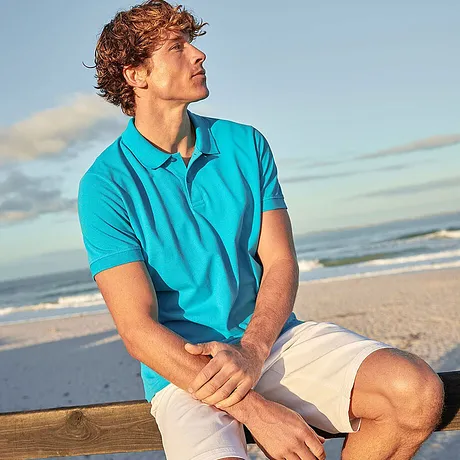 Sommerlicher Strandlook: Türkisfarbenes Poloshirt und helle Shorts für entspannte Urlaubsatmosphäre am Meer.