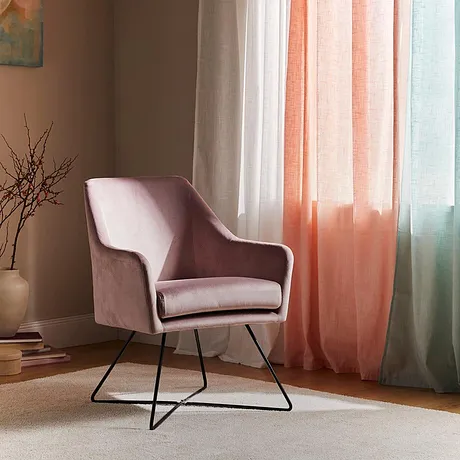 Fauteuil rose élégant devant des rideaux légers aux couleurs pastel. Des combinaisons de couleurs harmonieuses pour une ambiance cosy.