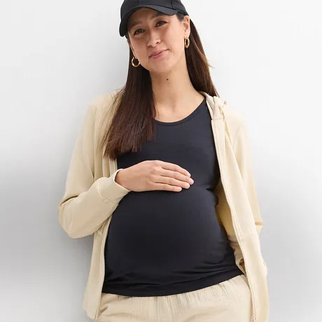 Mode confortable pour les futures mamans : un cardigan en maille et un pantalon crème, un top sombre et une casquette sportive.