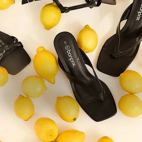 Élégantes sandales noires, entourées de citrons jaunes.