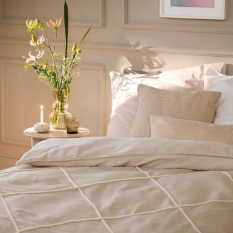 Une parure de lit claire à motif géométrique décore le lit. Des coussins blancs créent une ambiance chaleureuse.