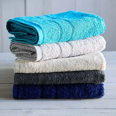 Une pile de serviettes douces dans différents coloris : turquoise, blanc, beige, gris foncé et bleu marine.