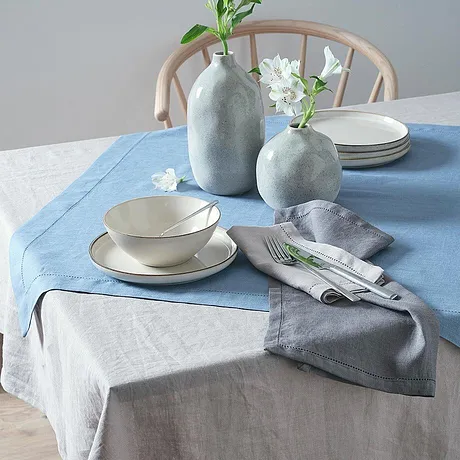 Des nappes bleues et grises décorent la table, des vases clairs et épurés finalisent l'ambiance.