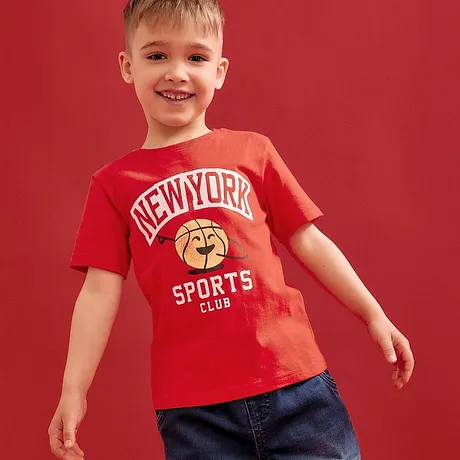 T-shirt rouge avec imprimé "New York Sports Club", associé à un jean bleu.