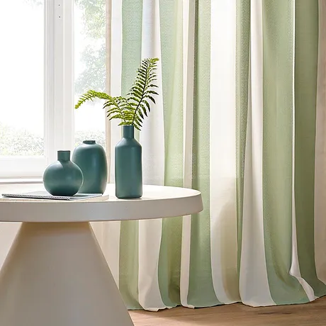 Un rideau clair dans des tons vert pastel et blanc apporte une touche déco élégante à la pièce.