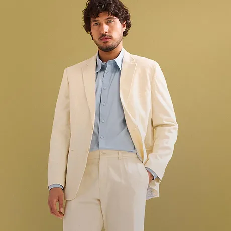 Eleganter cremefarbener Anzug mit hellblauem Hemd und weißen Sneakers.