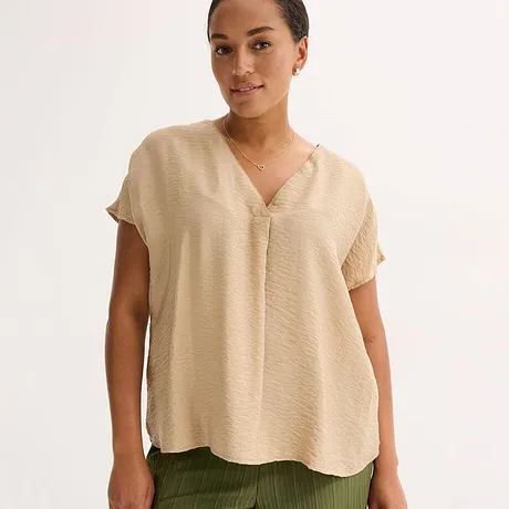 Beige, luftige Bluse mit V-Ausschnitt und kurzen Ärmeln, kombiniert mit olivgrüner Hose.