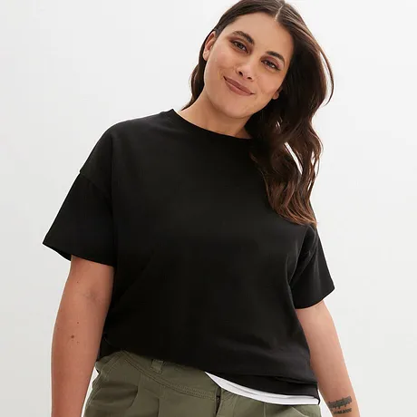 Ein schlichtes schwarzes T-Shirt mit Rundhalsausschnitt und kurzen Ärmeln, kombiniert mit einer olivgrünen Hose.