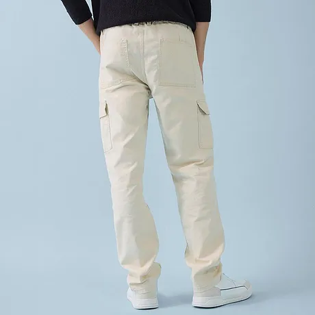 Tenue décontractée composée d'un pull noir et d'un pantalon cargo clair.
