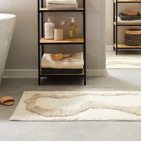 Des serviettes de toilette moelleuses et un tapis de bain douillet apportent confort et douceur dans une salle de bain à l'ambiance élégante.