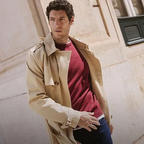 Manteau beige élégant sur un pull rouge et jean. Un look urbain décontracté pour l'automne.