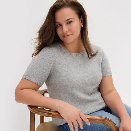Grauer Kurzarm-Pullover, kombiniert mit einer blauen Jeans.