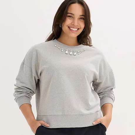 Graues Sweatshirt mit funkelnden Schmucksteinen als Verzierung am Kragen.