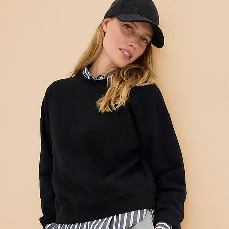 Sweat-shirt noir associé à une chemise rayée et une casquette de baseball cool. 