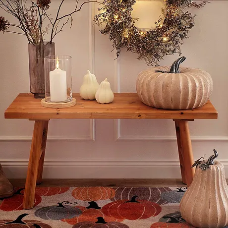 Herbstliche Dekoration mit Kürbissen und Kranz, warme Farben und natürliche Materialien dominieren.