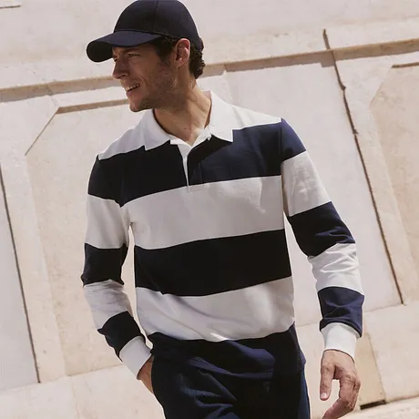 Pull bleu marine à rayures blanches et pantalon beige.