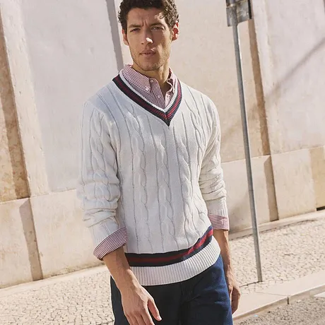 Weißer Strickpullover mit V-Ausschnitt, dunkle Jeans und weiße Sneaker.