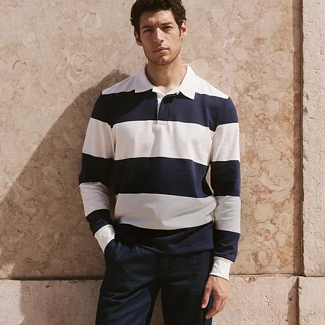 Klassischer Look mit gestreiftem Rugby-Sweat-Shirt, dunkler Hose und weißen Sneakers. 