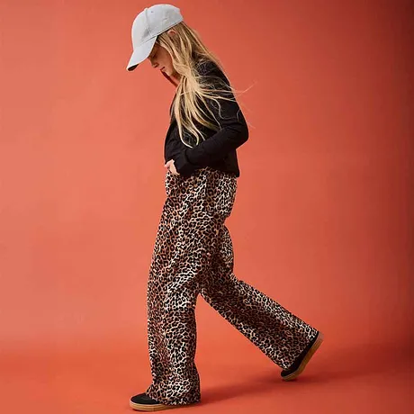 Pull noir et pantalon léopard stylé. Une casquette blanche finalise le look décontracté.