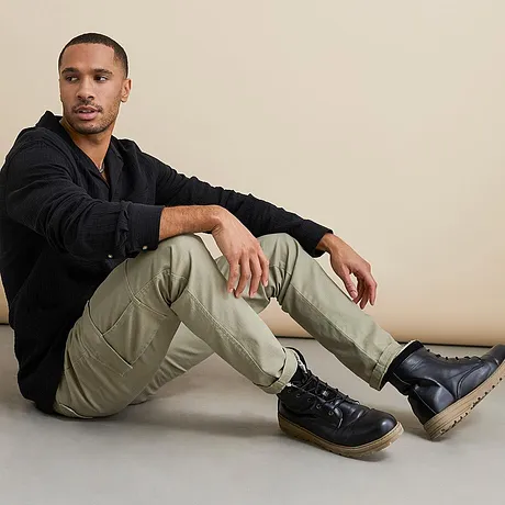 Haut noir et pantalon cargo beige associés à des bottines à lacets noires. 