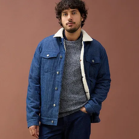 Veste en jean bleue avec doublure en polaire, pull gris et jean foncé.