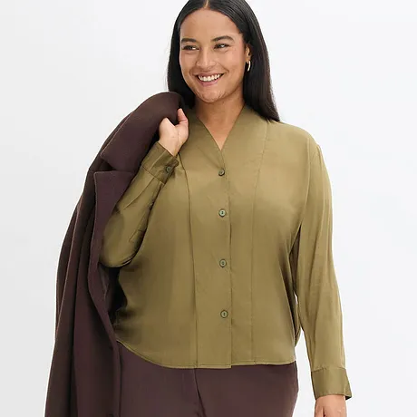 Tenue élégante composée d'un chemisier vert olive et d'un manteau marron.
