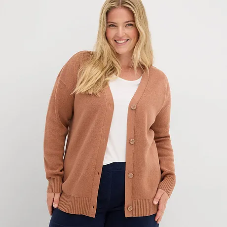 Gilet en maille couleur rouille sur un top blanc, associé à un jean foncé.