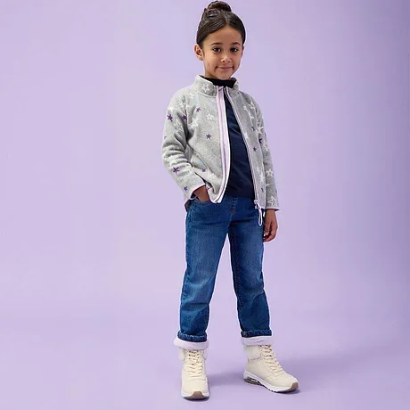 Veste imprimée, T-shirt foncé et jean complétés d'une paire de bottes blanches.