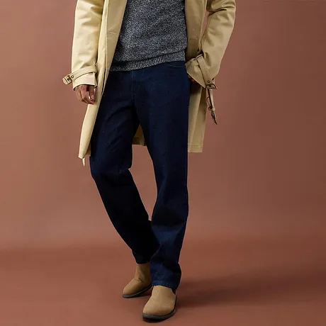 Manteau beige, pull gris, pantalon foncé et chaussures marron.