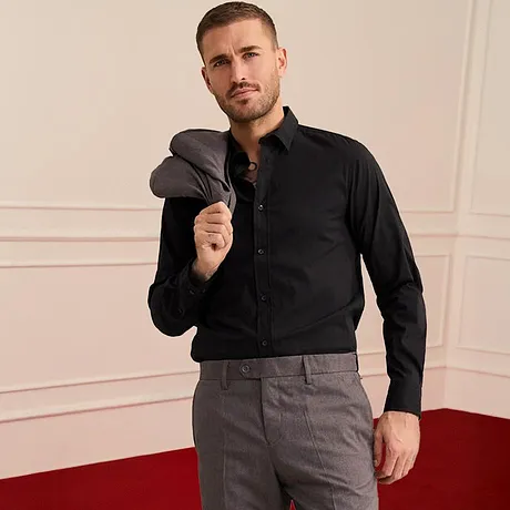 Look élégant avec chemise noire et pantalon gris.