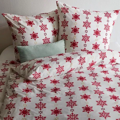 Parure de lit avec des flocons de neige rouge sur un fond blanc.