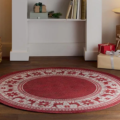 Un tapis rouge festif recouvre le sol tandis que des décorations de Noël trônent sur une étagère.