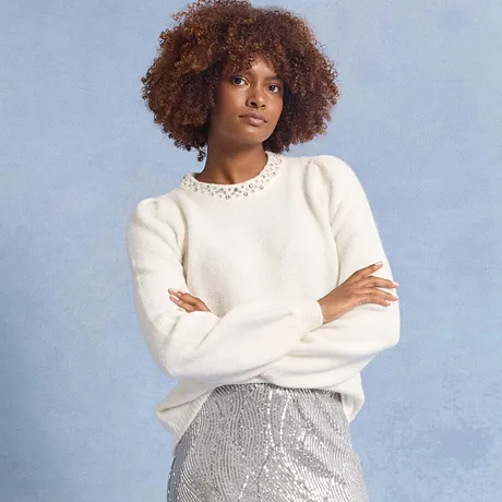 Weißer Pullover mit Spitzenkragen, kombiniert mit einem glitzernden silbernen Rock.