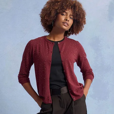 Rote Strickjacke mit glitzernden Verzierungen, kombiniert mit schwarzem Oberteil.