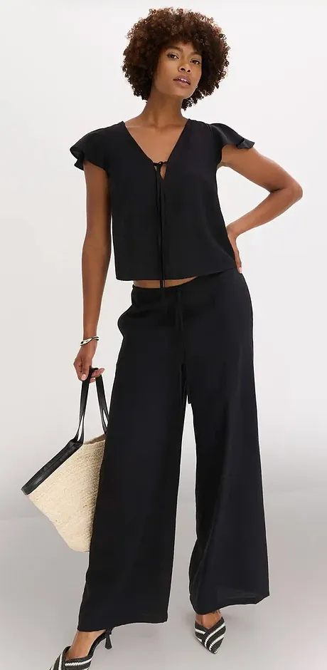 Ensemble élégant en noir : un haut à manches volantées et un large pantalon palazzo.
