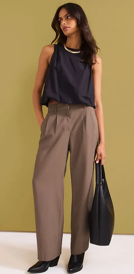 Tenue composée d'un top dos nu foncé, d'un pantalon large beige et d'un sac à main noir.