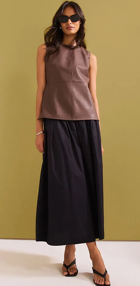 Tenue élégante avec top sans manches marron et jupe longue noire.