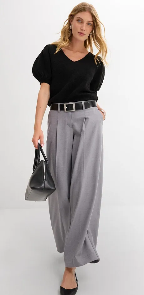 Eleganter Look mit schwarzer Bluse, weiten grauen Hosen und stilvollem Gürtel.