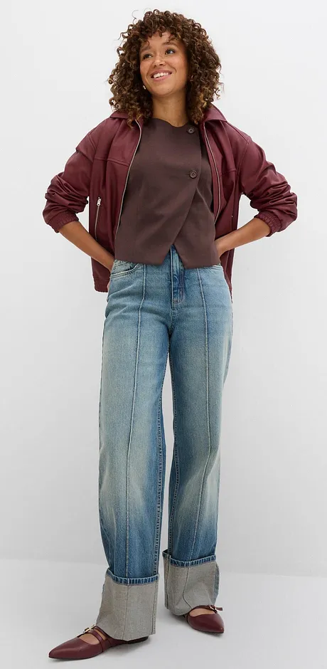 Lässiger Herbstlook mit weinroter Jacke, grauem T-Shirt und weiten Jeans mit Umschlag.