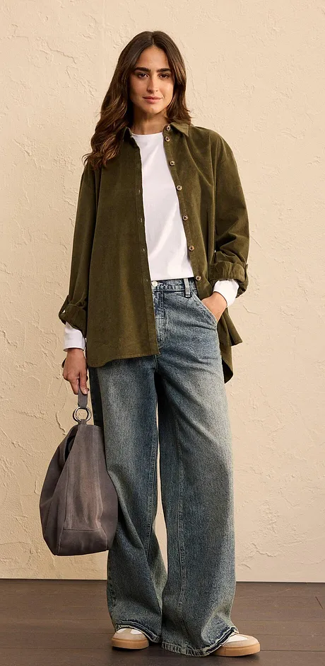 Look composé d'une chemise oversize vert olive, un T-shirt blanc et un jean large.