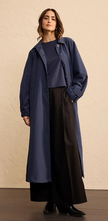 Manteau long élégant couleur bleu foncé, associé à un pantalon large et un haut sobre.