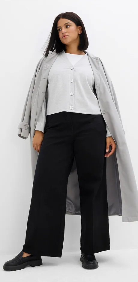 Grauer Mantel über weißer Bluse und weiten schwarzen Hosen.