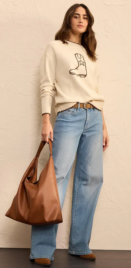 Pull de couleur crème avec imprimé botte, jean large et grand sac marron.