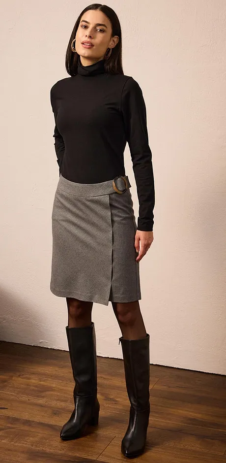 Look élégant avec pull à col roulé noir, jupe grise et bottes noires.